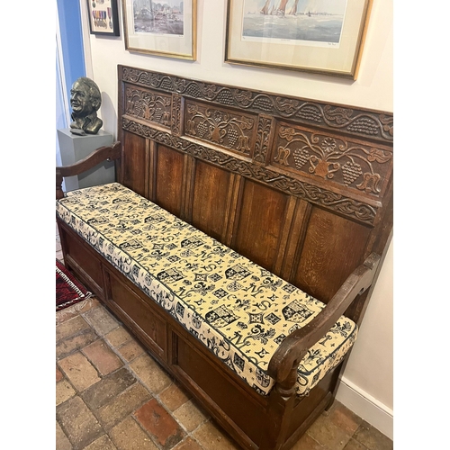 329 - An antique mixed wood box settle with carved back panel, with later upholstered cushion, approx. len... 