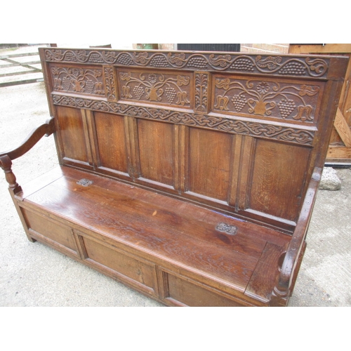 329 - An antique mixed wood box settle with carved back panel, with later upholstered cushion, approx. len... 