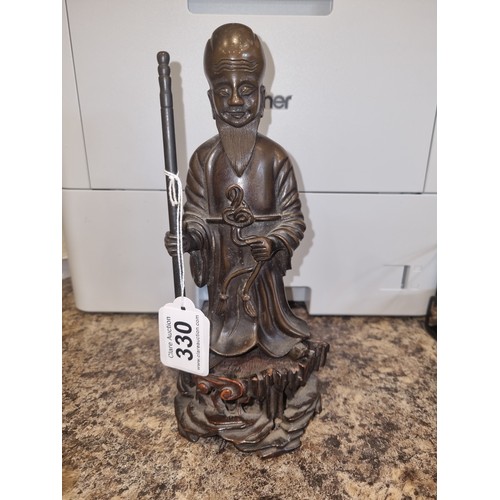 330 - An antique cast bronze figure of an oriental deity on carved wood stand,