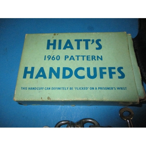 33 - Two pairs of police handcuffs, one set boxed dated 1960, both with leather holders and keys