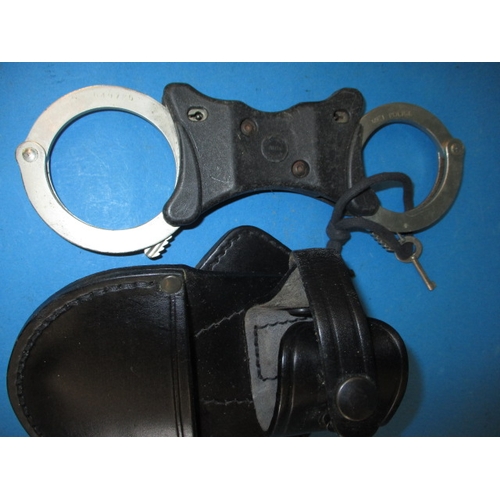 33 - Two pairs of police handcuffs, one set boxed dated 1960, both with leather holders and keys