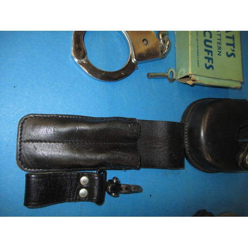 33 - Two pairs of police handcuffs, one set boxed dated 1960, both with leather holders and keys