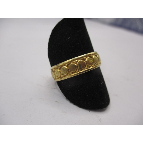 42 - A 750 yellow gold wedding band with geometric pattern, approx. ring size ‘R’ approx. width 5.7mm, ap... 