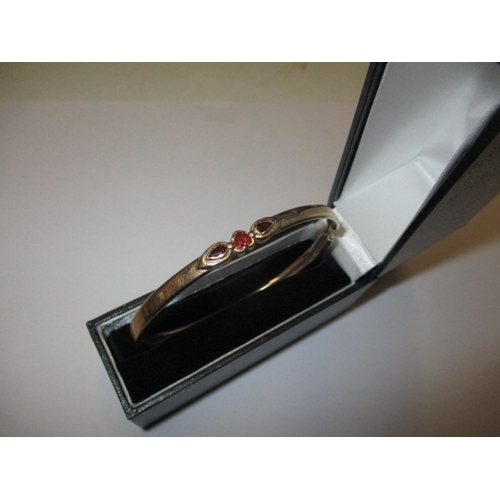 80 - A 9ct yellow gold bangle with 3 garnets, approx. weight 8.4g, in useable pre-owned condition with on... 