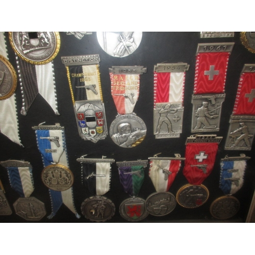 272 - A framed collection of 1950’s 60’s shooting medals, one mans awards who was Switzerland’s champion m... 