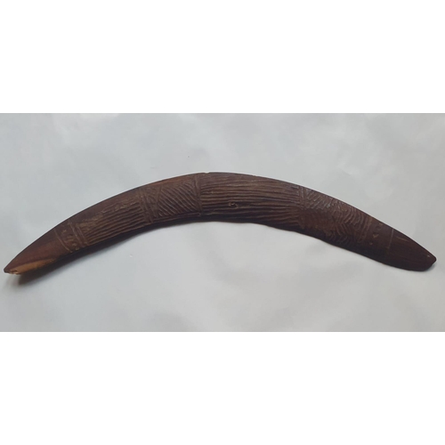 63 - An antique Aboriginal boomerang, carved to one side with linear designs, 16.75