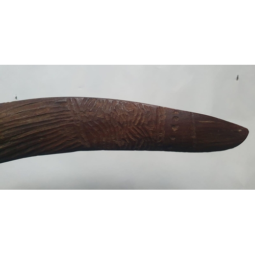 63 - An antique Aboriginal boomerang, carved to one side with linear designs, 16.75