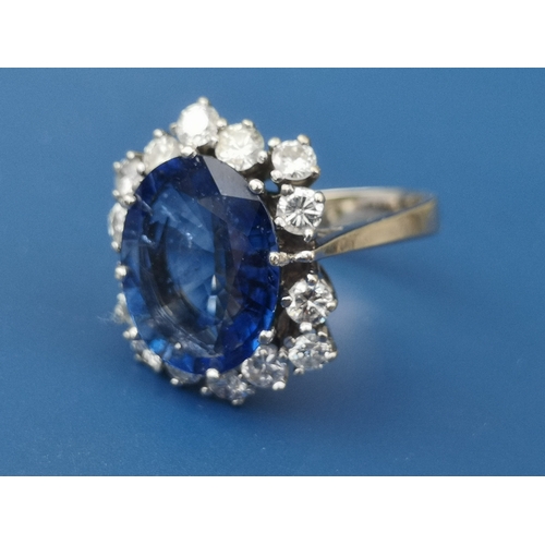 200 - A modern sapphire & diamond set cluster ring, the oval claw set sapphire weighing approximately 4 ca... 