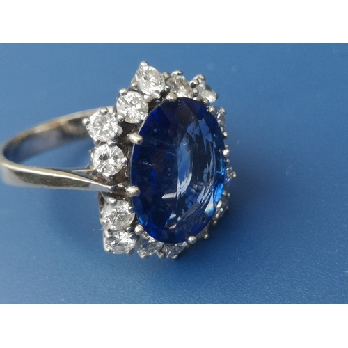 200 - A modern sapphire & diamond set cluster ring, the oval claw set sapphire weighing approximately 4 ca... 