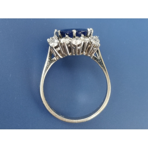 200 - A modern sapphire & diamond set cluster ring, the oval claw set sapphire weighing approximately 4 ca... 