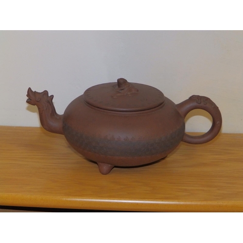 49 - An Oriental red stoneware teapot, having dragon mask spout, incised band of decoration to the low gl... 