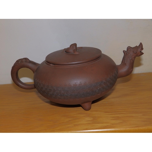 49 - An Oriental red stoneware teapot, having dragon mask spout, incised band of decoration to the low gl... 