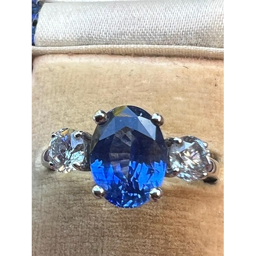 210 - A three stone sapphire & diamond ring, the four-claw set cushion cut sapphire weighing approximately... 