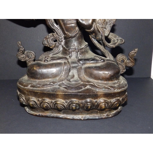 116 - An old Eastern bronze seated deity on copper base, 11.25