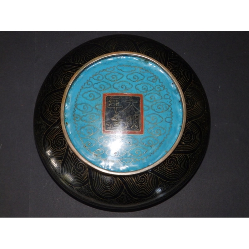 122 - A 19thC Oriental black ground cloisonne dragon bowl on wooden stand, the exterior displaying two con... 