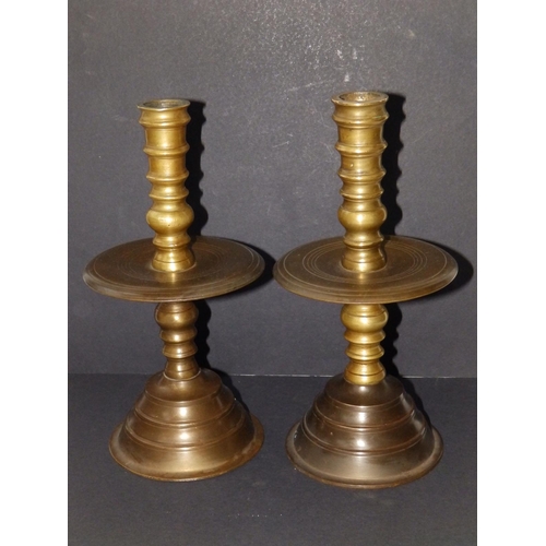 123 - A near pair of late 17thC turned brass candlesticks in Heemskirk style, the stems of ring turned for... 