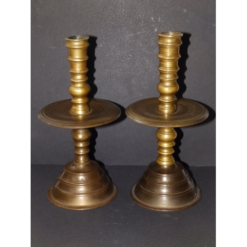 123 - A near pair of late 17thC turned brass candlesticks in Heemskirk style, the stems of ring turned for... 