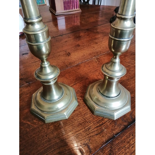 107 - A pair of tall antique brass candlesticks, having drip pans above slender stems to octagonal bases, ... 