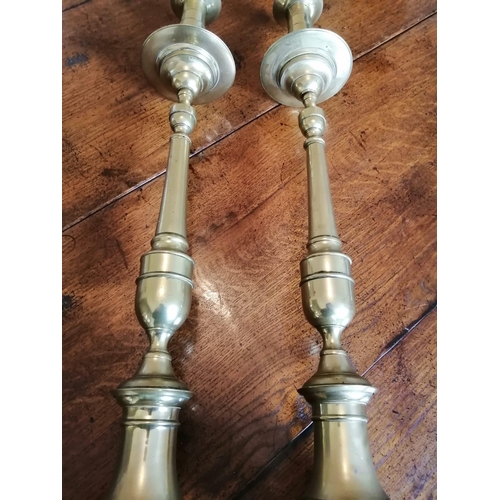 107 - A pair of tall antique brass candlesticks, having drip pans above slender stems to octagonal bases, ... 