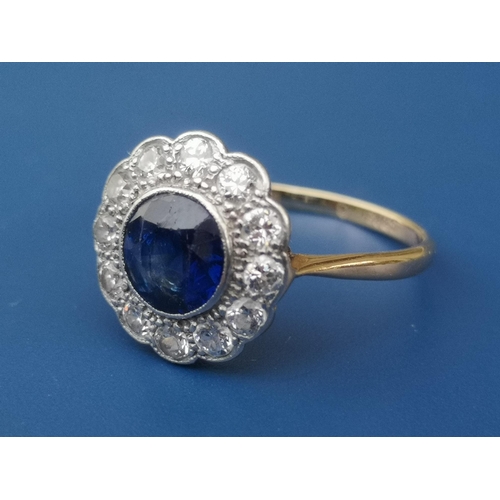 214 - A circular sapphire & diamond cluster ring, the sapphire measuring approximately 6mm diameter - '18c... 