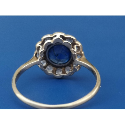 214 - A circular sapphire & diamond cluster ring, the sapphire measuring approximately 6mm diameter - '18c... 