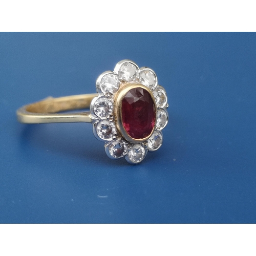 216 - An oval ruby & diamond cluster set 18ct gold ring.  Finger size P.