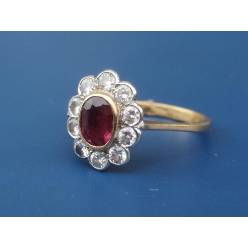 216 - An oval ruby & diamond cluster set 18ct gold ring.  Finger size P.