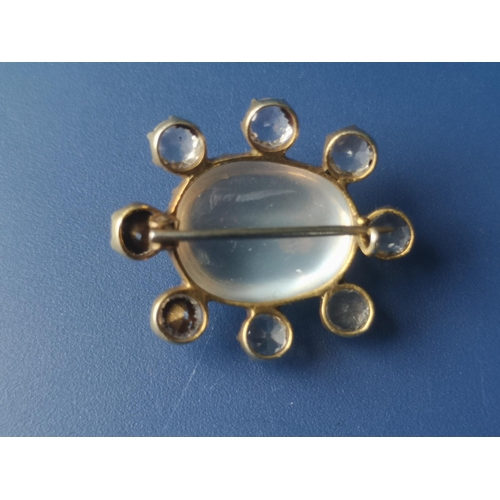 217 - An oval moonstone cluster brooch, surrounded by seven colourless stones and one replacement paste, i... 