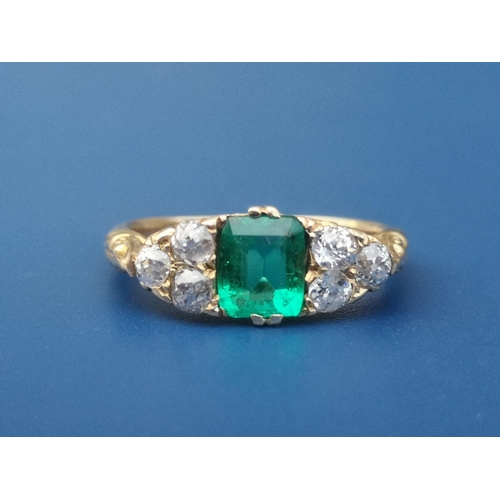 231 - An emerald & diamond ring, the rectangular cut emerald flanked by six small old cut diamonds on yell... 