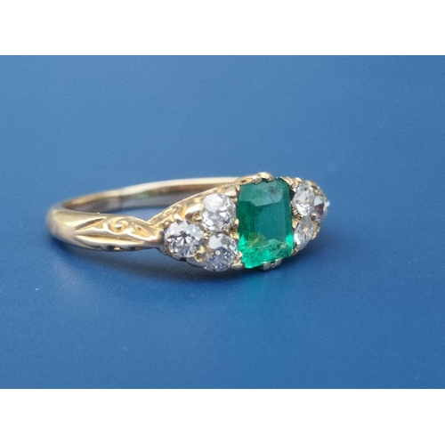 231 - An emerald & diamond ring, the rectangular cut emerald flanked by six small old cut diamonds on yell... 