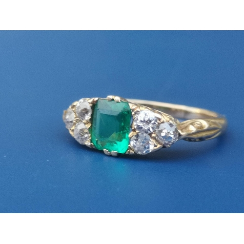 231 - An emerald & diamond ring, the rectangular cut emerald flanked by six small old cut diamonds on yell... 