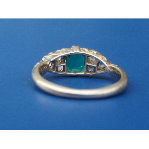 231 - An emerald & diamond ring, the rectangular cut emerald flanked by six small old cut diamonds on yell... 