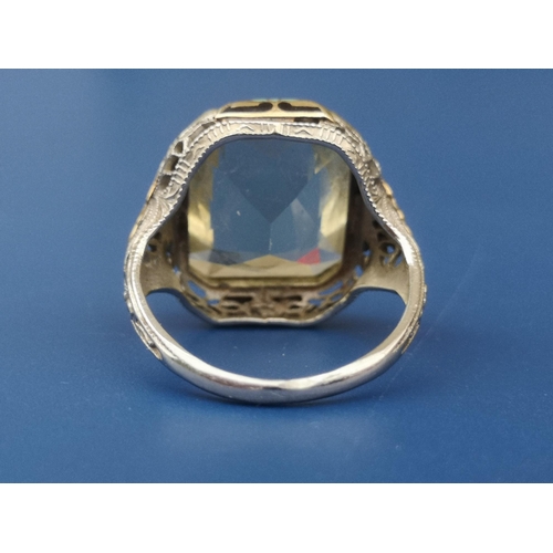 245 - A solitaire ring set with a large rectangular cut pale yellow stone, having art deco style coloured ... 