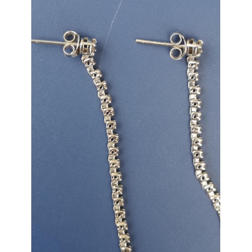 253 - A pair of long drop diamond set 18ct white gold earrings of chain form, set with numerous small diam... 