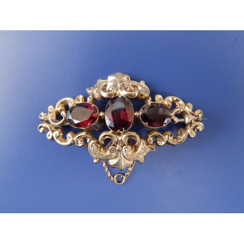 269 - A Victorian garnet set yellow metal brooch of open scroll form, 2.25