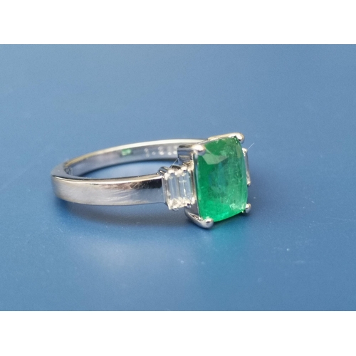 274 - A rectangular cut emerald & diamond ring , the central four-claw set emerald flanked by four small d... 