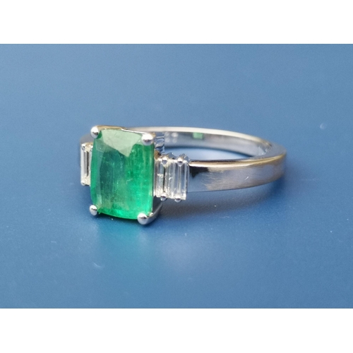 274 - A rectangular cut emerald & diamond ring , the central four-claw set emerald flanked by four small d... 