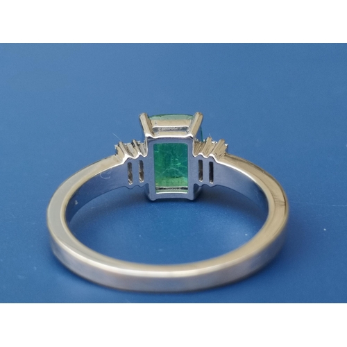 274 - A rectangular cut emerald & diamond ring , the central four-claw set emerald flanked by four small d... 