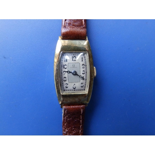 302 - An art deco lady's gold Omega wrist watch in tonneau shaped case on replacement leather strap.