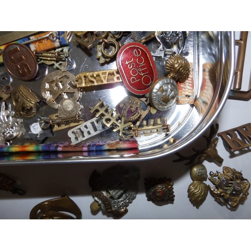 53 - A tin containing a large collection of military, badges, shoulder titles etc.