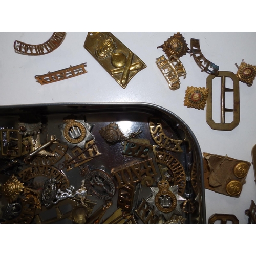 53 - A tin containing a large collection of military, badges, shoulder titles etc.