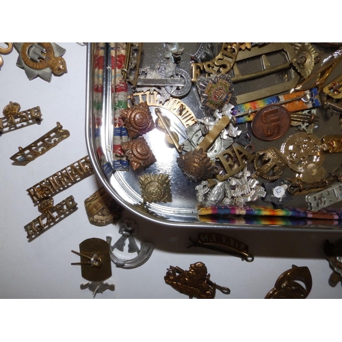 53 - A tin containing a large collection of military, badges, shoulder titles etc.