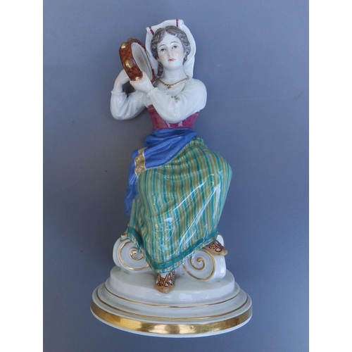 44 - A Meissen porcelain figure of a female tambourine player in folk costume, seated on an upturned Cori... 