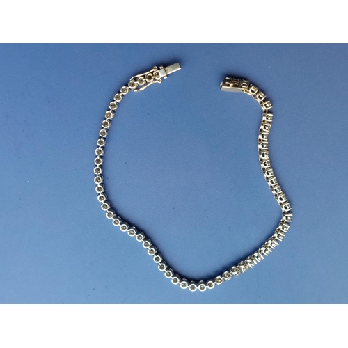 307 - A diamond set line bracelet, comprising 61 claw set stones - testing as 18ct white gold, 7.9