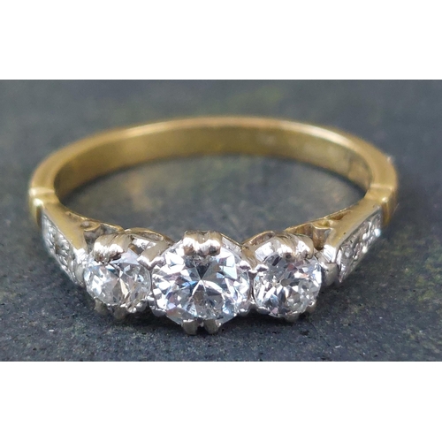 249 - A three stone  claw set diamond ring, small diamonds to shoulders, on 18ct. shank.  Finger size K.