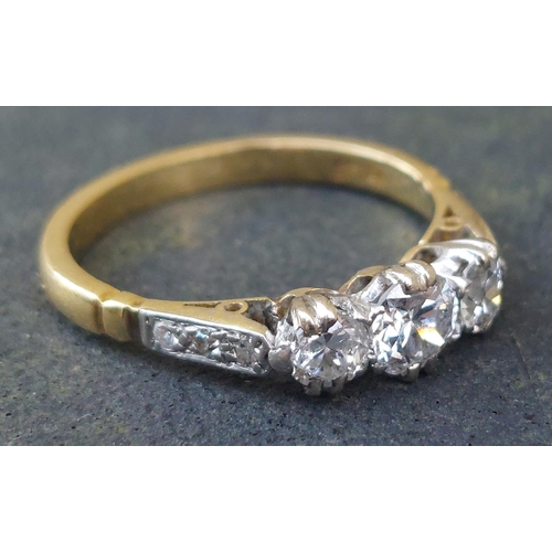 249 - A three stone  claw set diamond ring, small diamonds to shoulders, on 18ct. shank.  Finger size K.