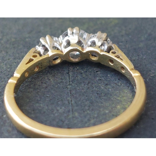 249 - A three stone  claw set diamond ring, small diamonds to shoulders, on 18ct. shank.  Finger size K.