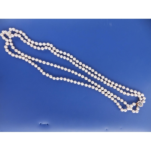 281 - A long twin strand pearl necklace, approximate pearl diameters 7.5mm, on 9ct gold cluster clasp, 31