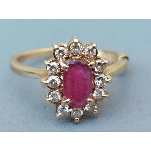 257 - An oval ruby & diamond cluster ring in 9ct gold.