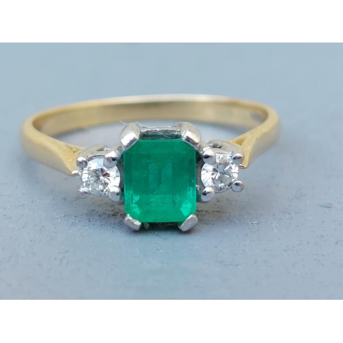 260 - A modern three stone emerald & diamond 18ct gold ring, the four-claw set rectangular cut emerald wei... 